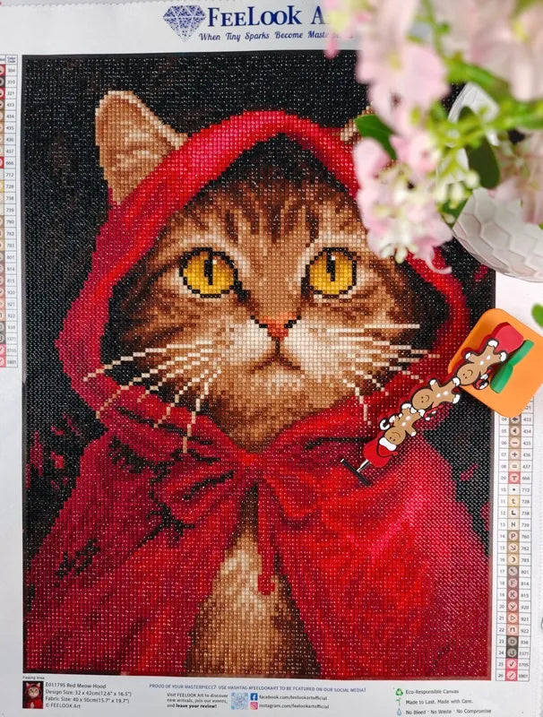 Red Meow-Hood 5D diamond painting canvas by FEELOOK Art, featuring a cute tabby cat wearing a bright red cloak, displayed with a gingerbread crafting pen - FEELOOK Art