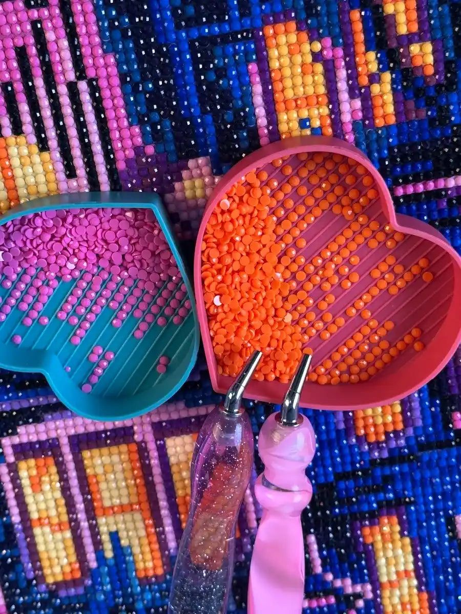 Pink and orange resin drills arranged in trays with diamond painting pens on a colorful completed canvas - FEELOOK Art