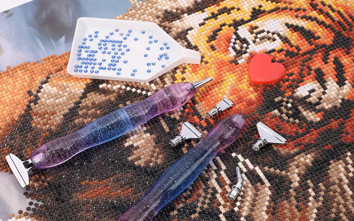 Diamond painting tools scattered on a finished canvas with vibrant round drills