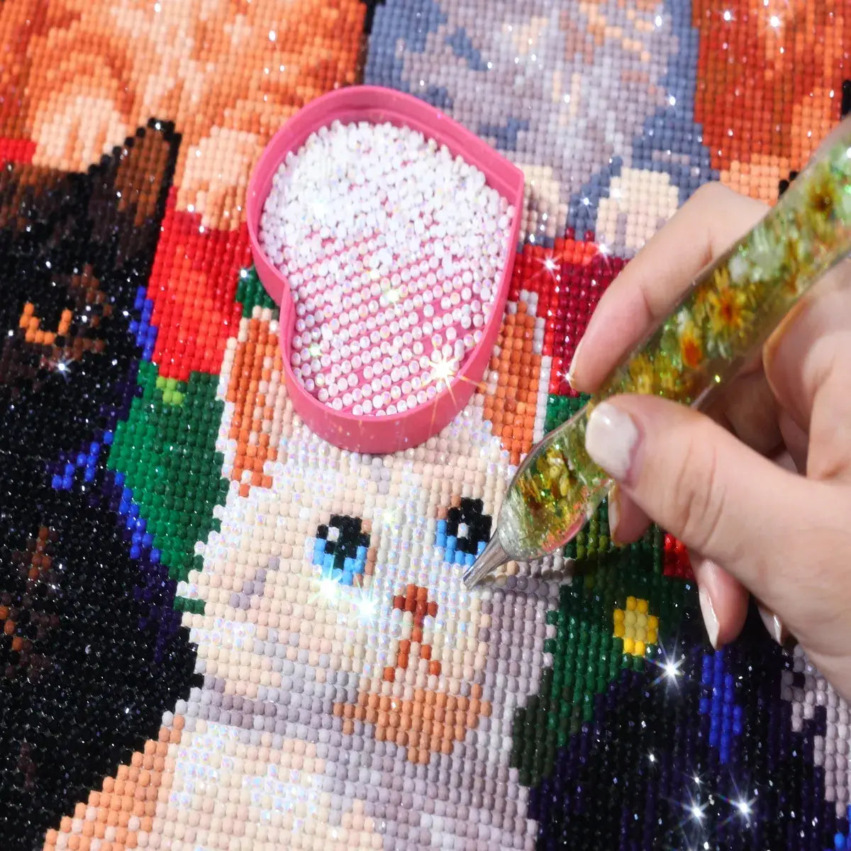 AB diamonds on the Kitten Christmas Tree diamond painting with a hand placing diamonds and an AB diamond tray - FEELOOK Art