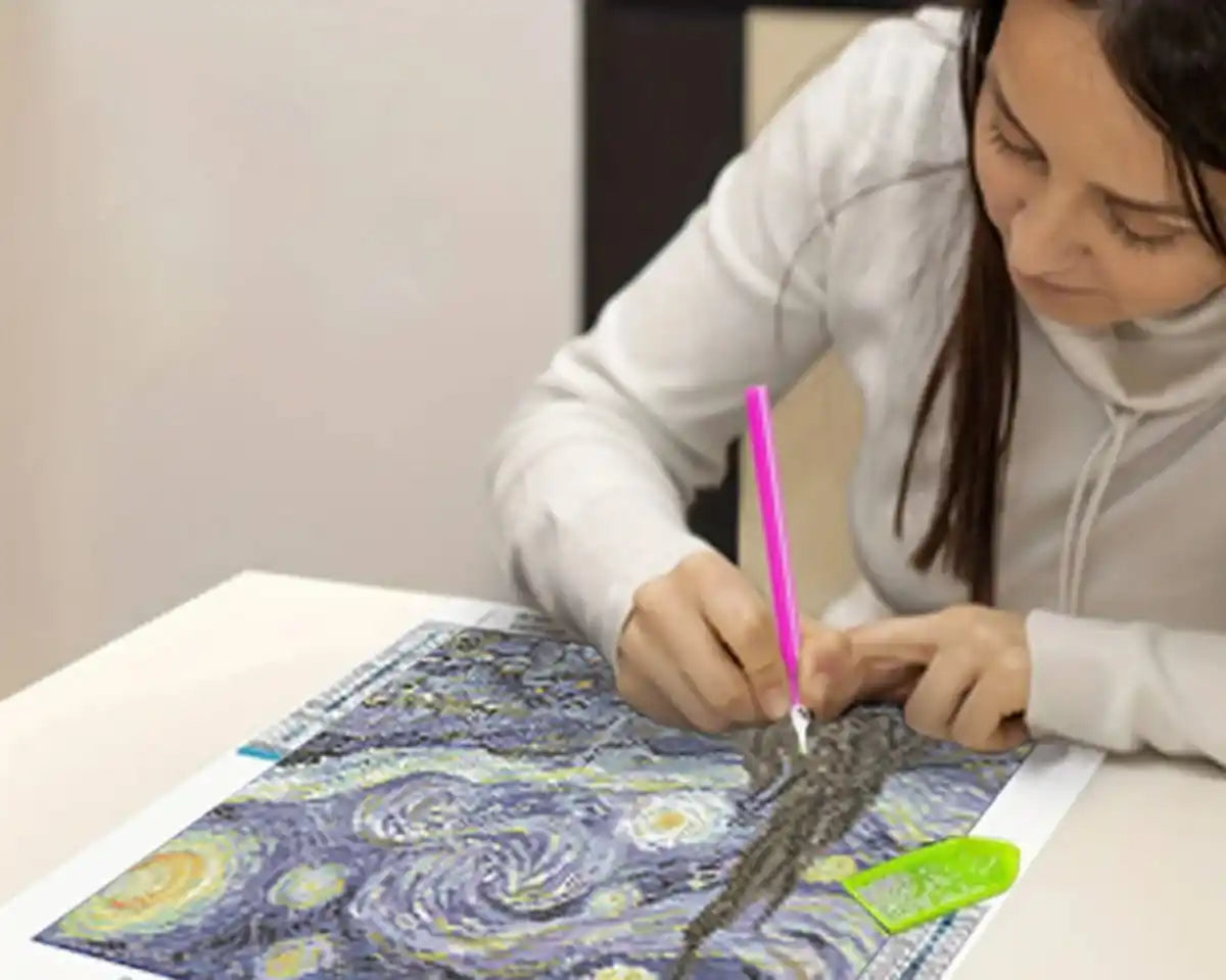 A person placing diamonds on a diamond painting canvas, showcasing the creative process.