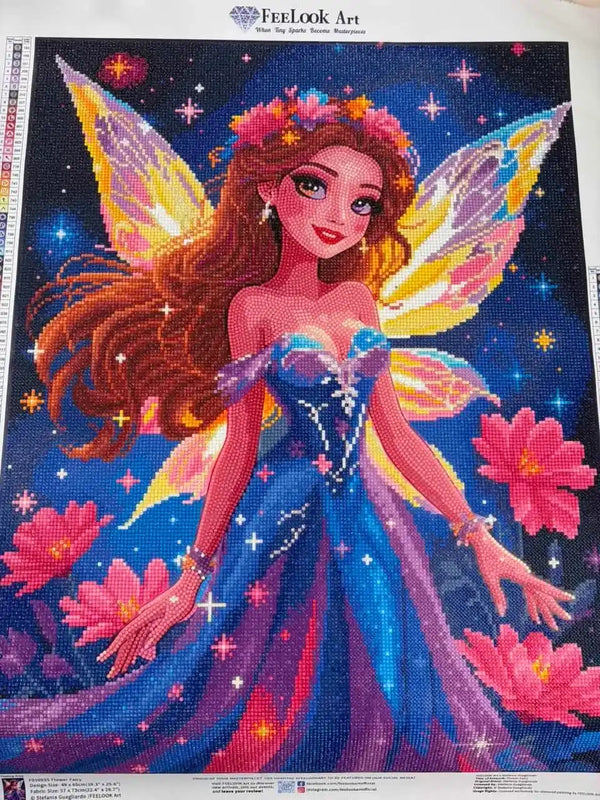 A colorful diamond painting or art print featuring a fairy with long brown hair, a blue and purple dress, pink flowers, and glowing wings on a starry blue background - FEELOOK Art