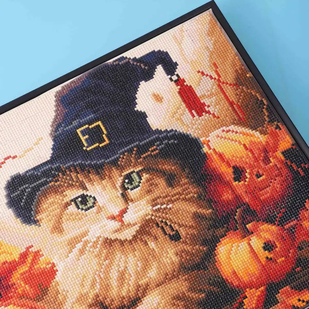 Close-up of orange cat face with Halloween hat in animal diamond painting art.