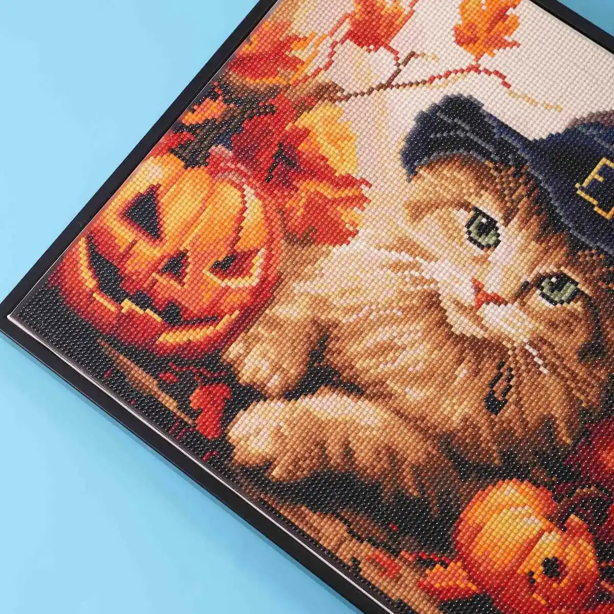 Sparkling detail of Halloween-themed diamond painting featuring orange cat.