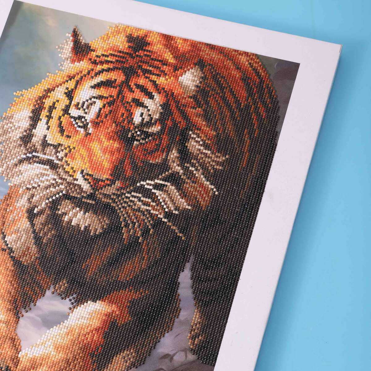 Detailed view of the Tiger’s eyes and fur, capturing the beauty of this majestic animal with the use of diamond painting supplies and techniques.